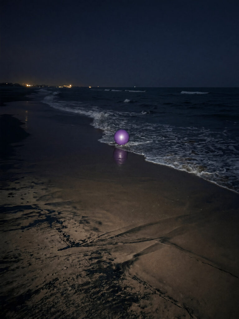 Un globo morado descansa cerca de la orilla cubierta de espuma en una playa en una noche oscura; su reflejo se ve en la arena húmeda y en el agua del mar que lo rodea.